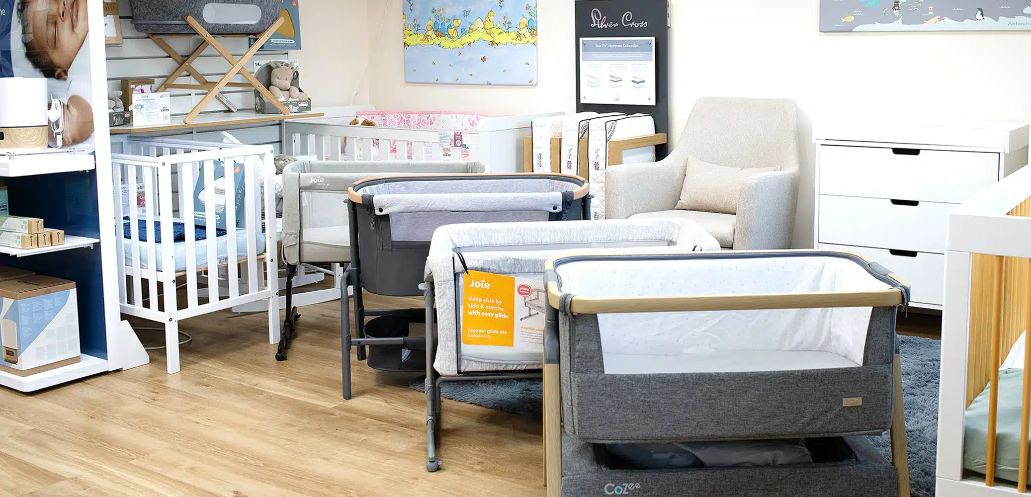 Display area in a baby store, featuring various baby cribs, nursery furniture, bassinets, and baby accessories