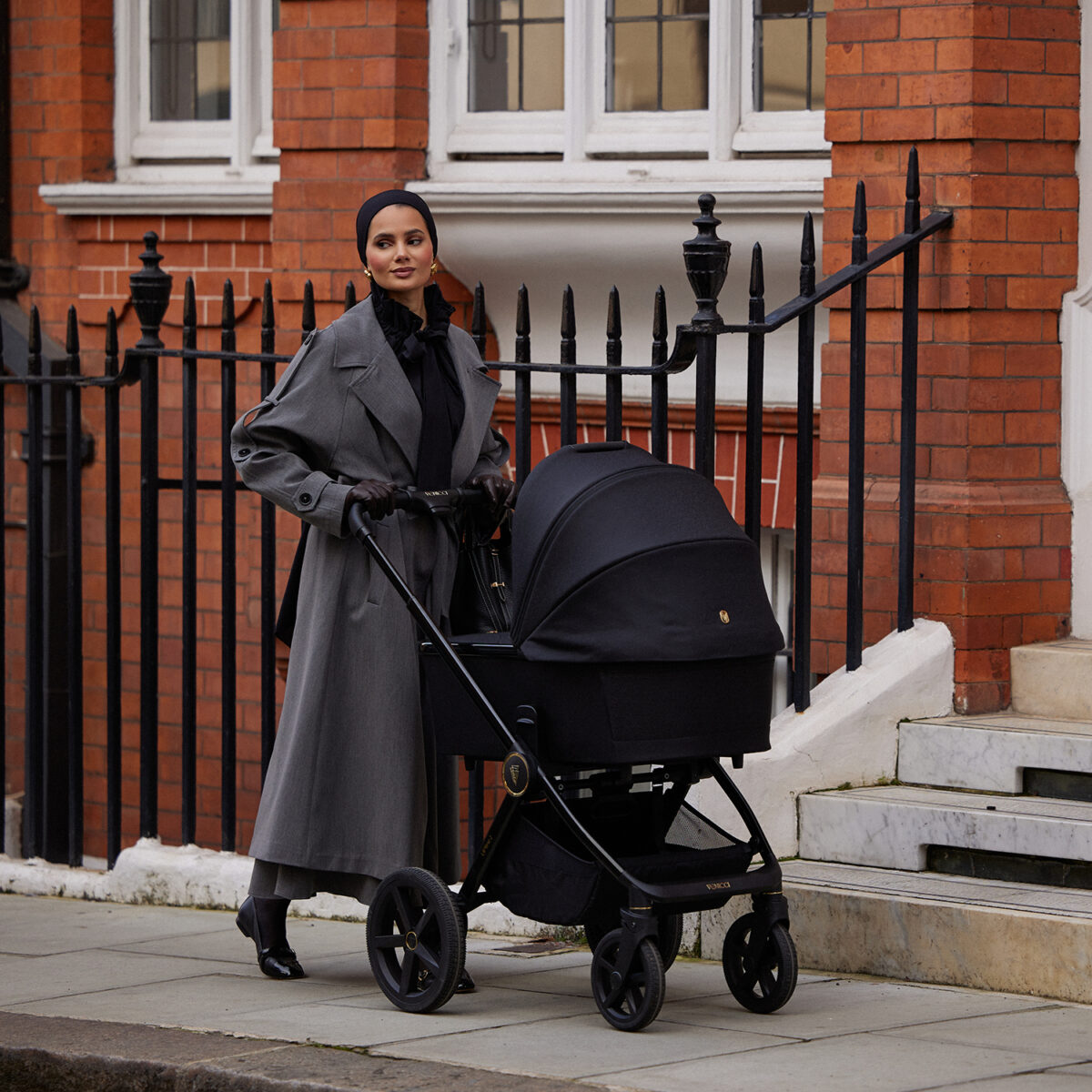 Mother pushching the Upline 2 Pushchair with carrycot installed on the side walk.