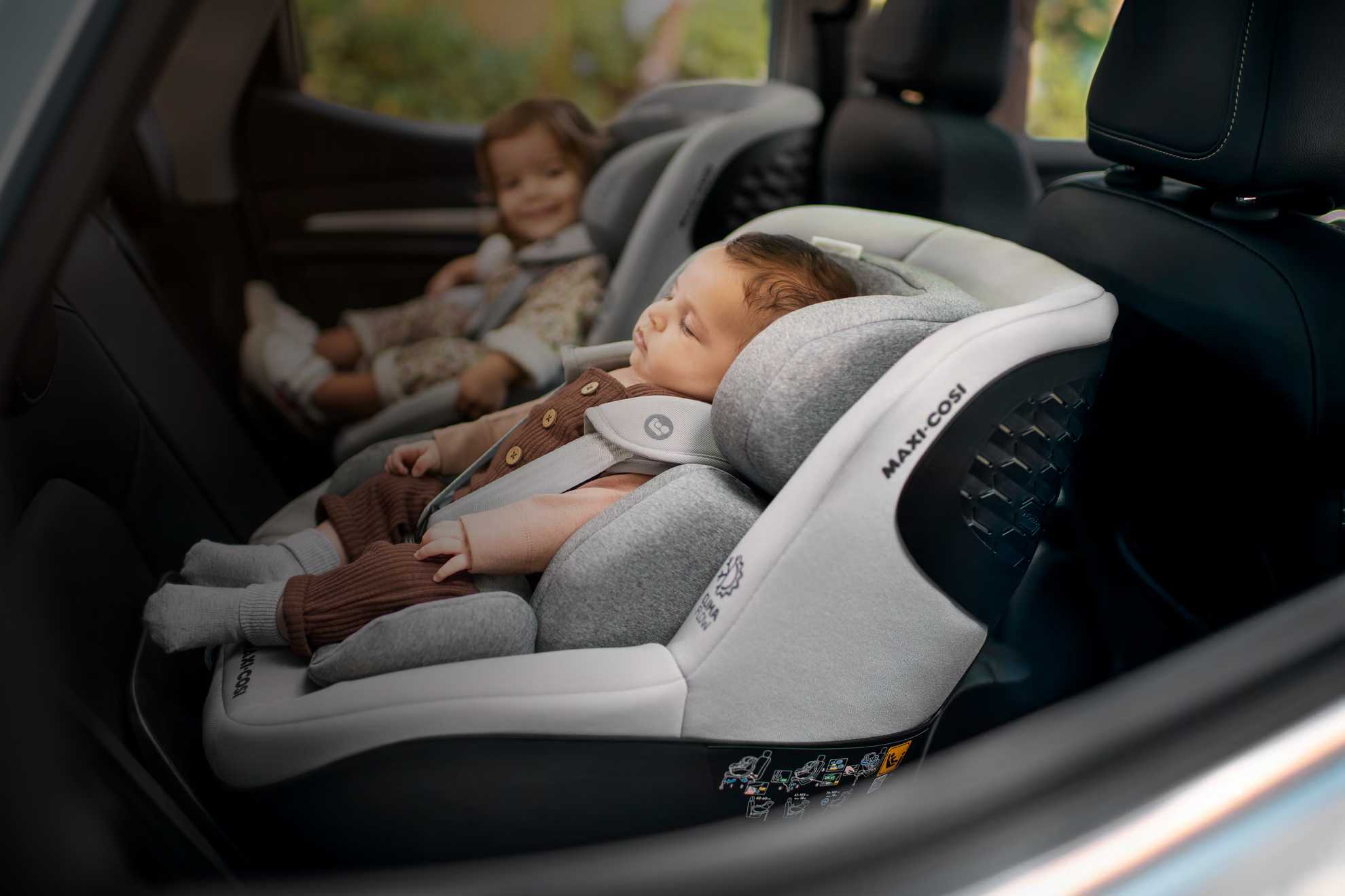 Two children strapped into car seat for car journey.