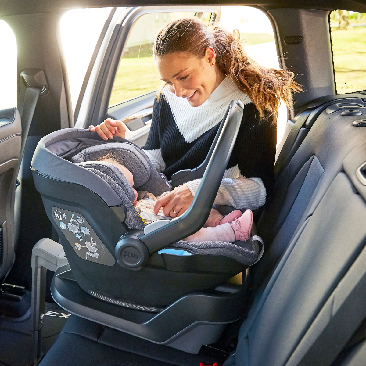 Parent preparing the baby i-Size Car Seat with base for travel.